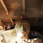 Close up photo of the Fremont Troll with people climbing on it.