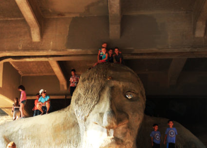 Close up of the Fremont Troll with people climbing on it.