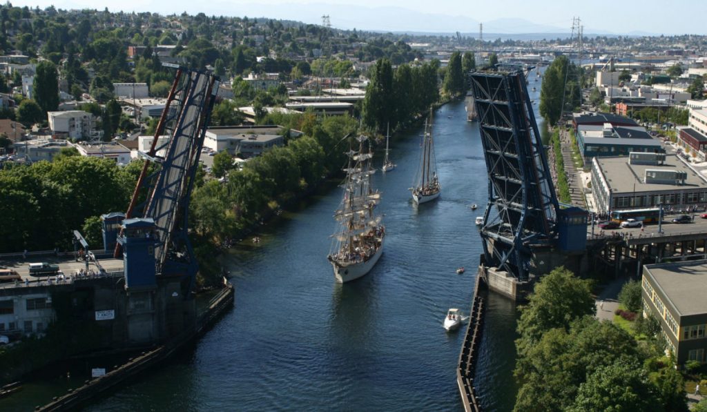 The ship canal with two ships and four small boats making their way under the open Fremont bridge