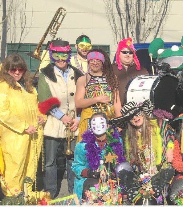 Group picture of people in colorful costumes with band instruments and masks.