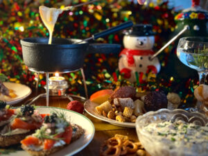A sampling of Santa Snacks including gravlax crostini, cheese fondue, smoked clam dip, chex mix and rum balls; and drinks from the Naughty List including a chocolate, toasted marshmallow, mezcal tiki drink named “Yippee-Ki-Yay Motherfluffer” and “Someone Special” their rosemary martini.